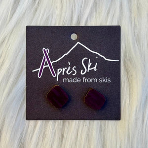 Pair of maroon earrings on a 'Après Ski' branded card against a light gray background