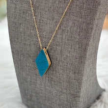 Necklace with a blue pendant on a gray mannequin bust against a blurred natural background