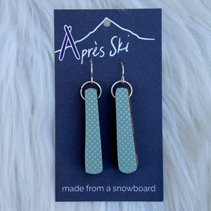 Teal earrings on a blue card with 'Après Ski' branding on a white fur background