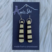 Pair of earrings on a blue card with 'Après Ski' branding against a fur background