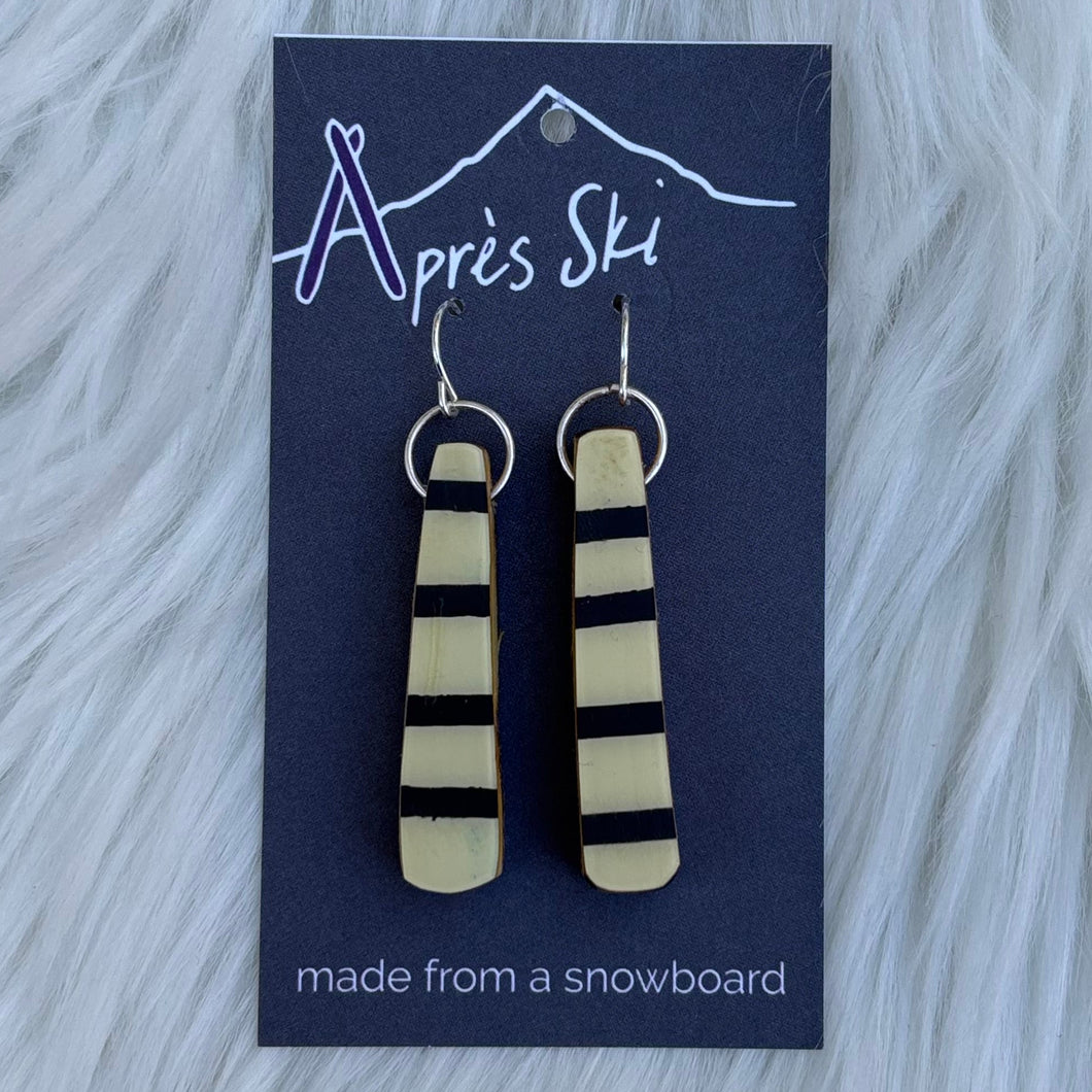 Pair of earrings on a blue card with 'Après Ski' branding against a fur background