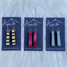 A selection of colorful snowboard earrings displayed on a card, with various snowboard designs represented in different colors.