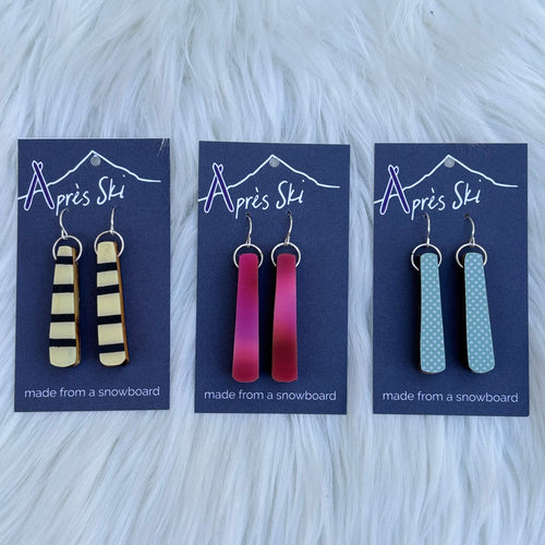 A selection of colorful snowboard earrings displayed on a card, with various snowboard designs represented in different colors.