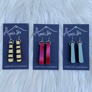 A selection of colorful snowboard earrings displayed on a card, with various snowboard designs represented in different colors.