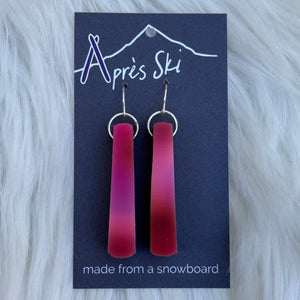 Red ombre earrings on a blue card with 'Apres Ski' branding, placed on a white fur background.